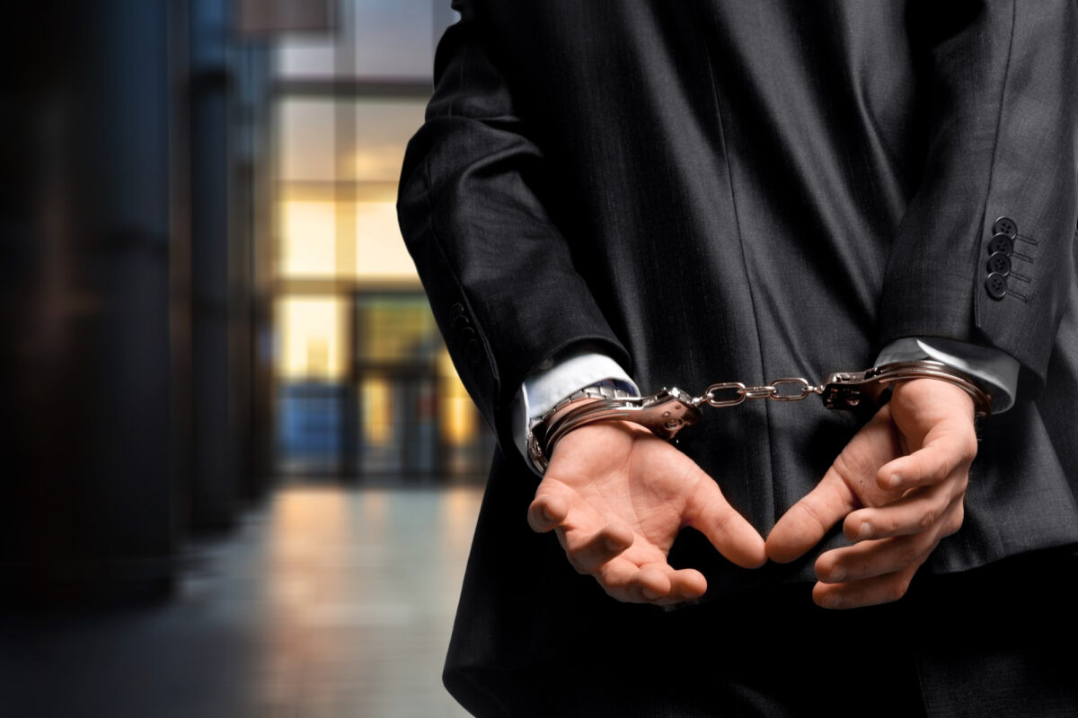 Man in a business suit wearing handcuffs symbolizing expungement in Oklahoma and clearing a criminal record legally