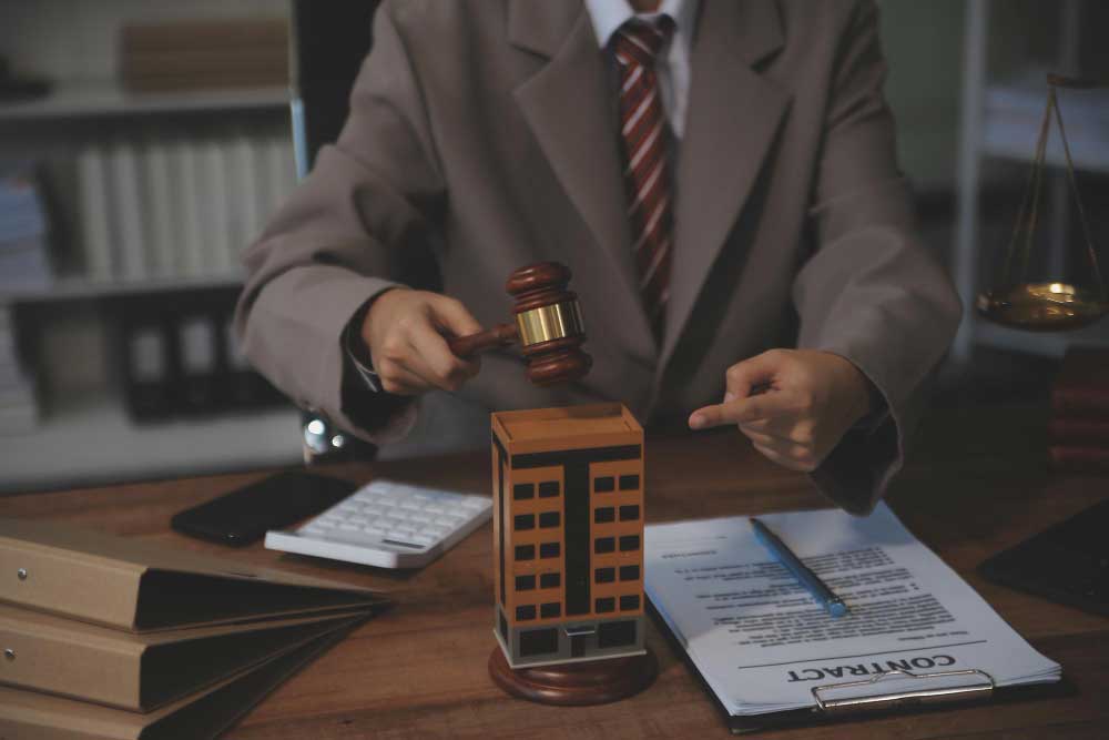 Attorney holding a gavel over a commercial building model representing civil law disputes in Oklahoma City